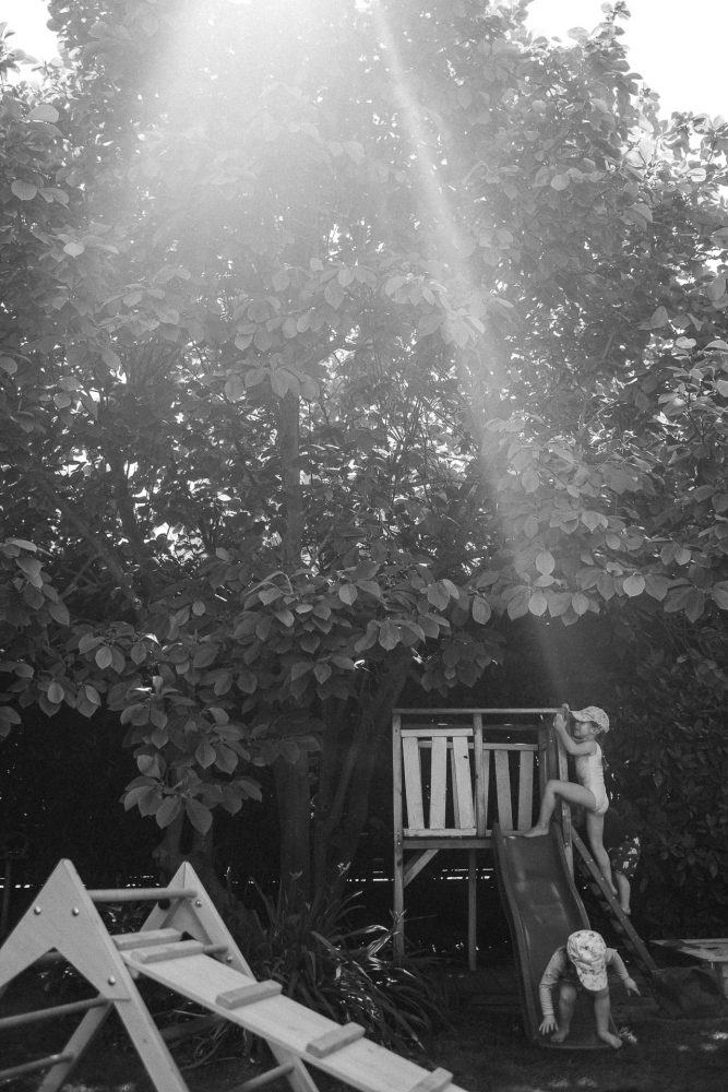 kleines Mädchen klettert im Sommer im Garten