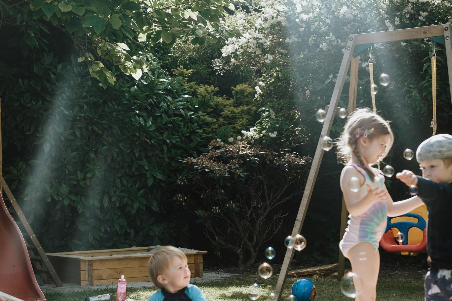 Kinder spielen im Sommer im Garten mit Seifenblasen