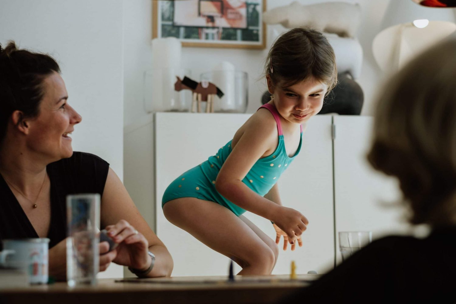 Mädchen und Mama spielen am Tisch ein Spiel
