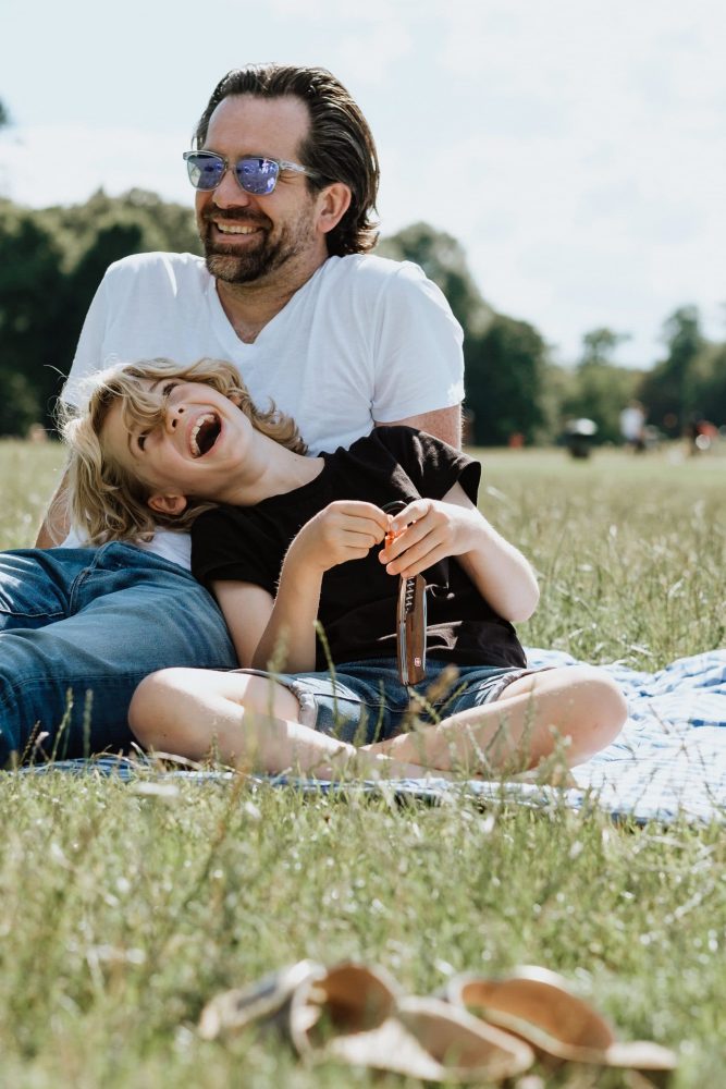 Vater und Sohn sitzen im Park auf einer Picknickdecke