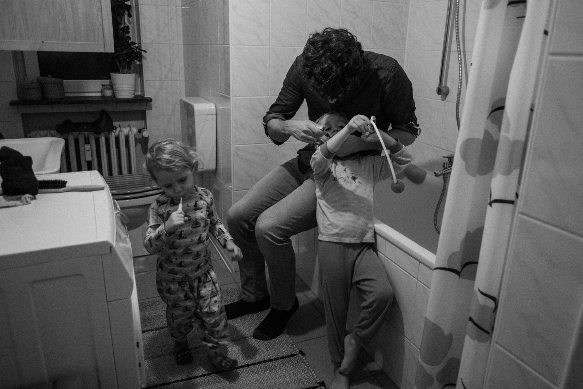 Papa putzt einem seiner Kinder die Zähne im Badezimmer