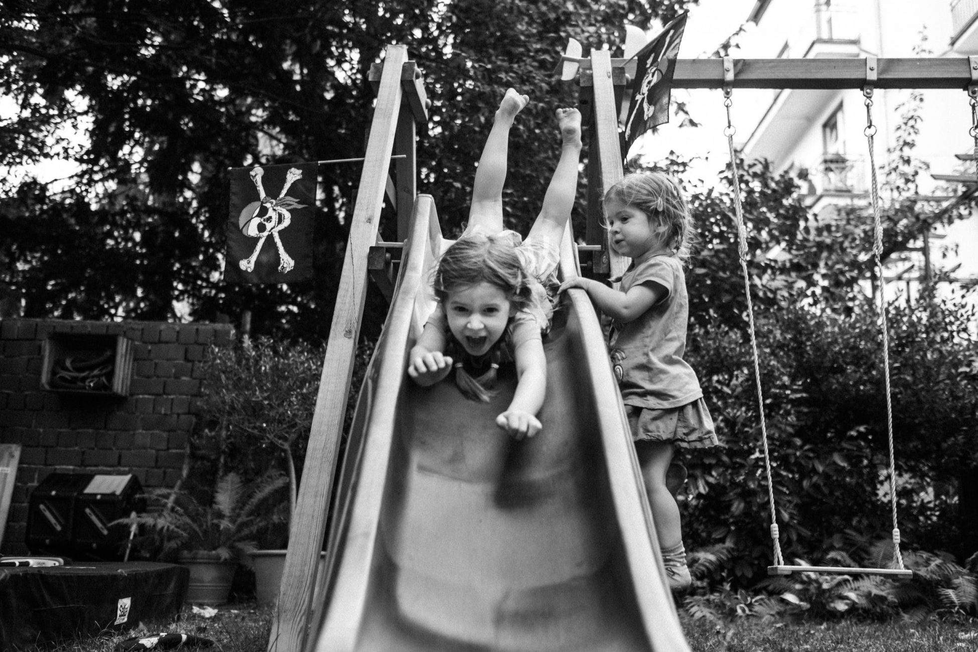 Mädchen rutscht auf dem Bauch die Rutsche herunter und freut sich