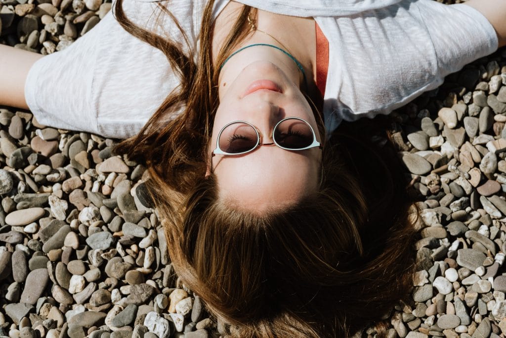 Frau liegt entspannt am Kieselstrand