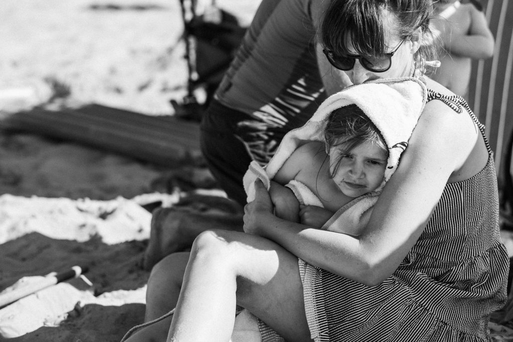 Mama und Kind kuscheln am Strand