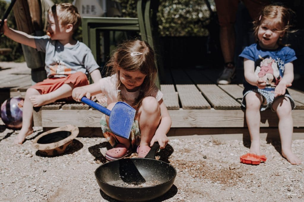 Drei Kinder spielen im Sand