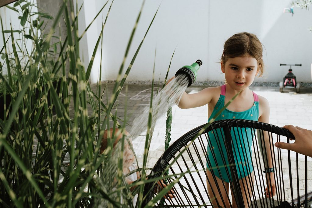 Kleines Mädchen wässert Pflanzen
