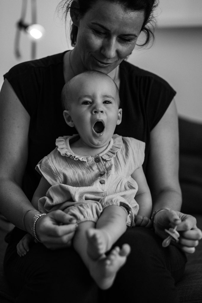 Kleines Baby gähnt auf Mamas Schoß