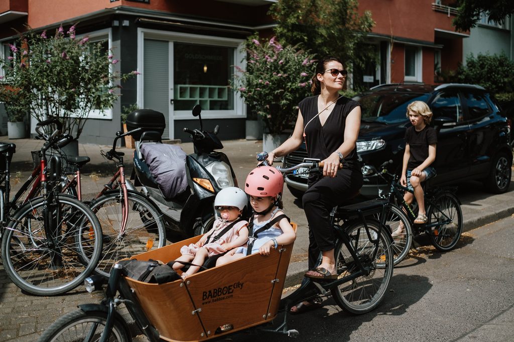 Mama fährt mit Lastenfahrrad und den Kindern los