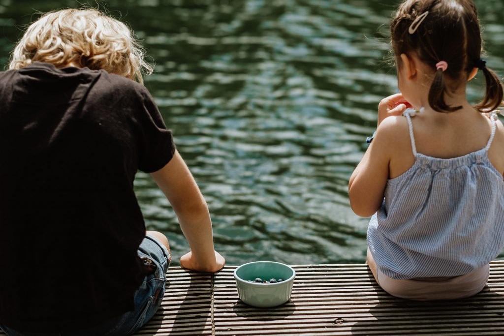 Geschwister sitzen am See