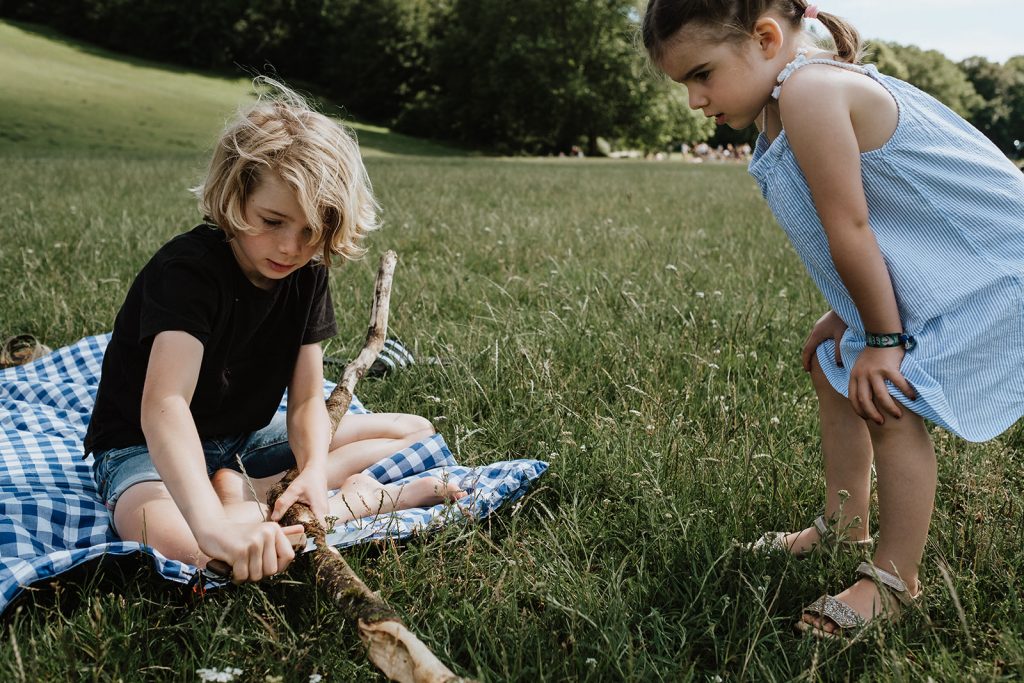 Junge schnitzt einen Stock im Park